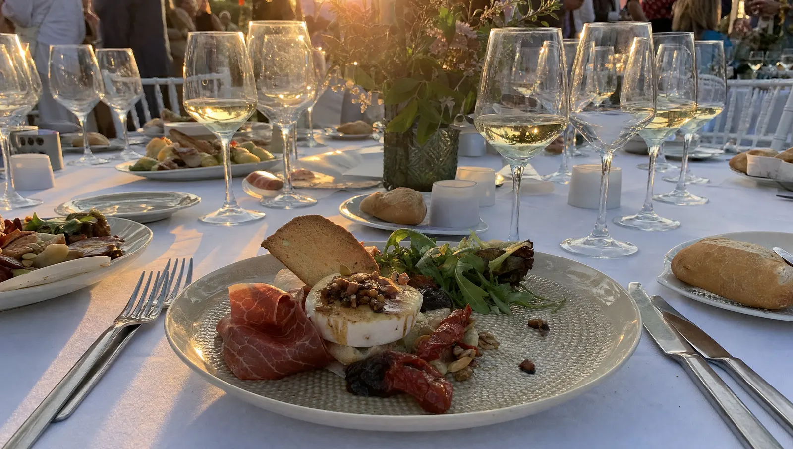 Mesa de banquete de boda con entrantes y copas de vino servidas al atardecer