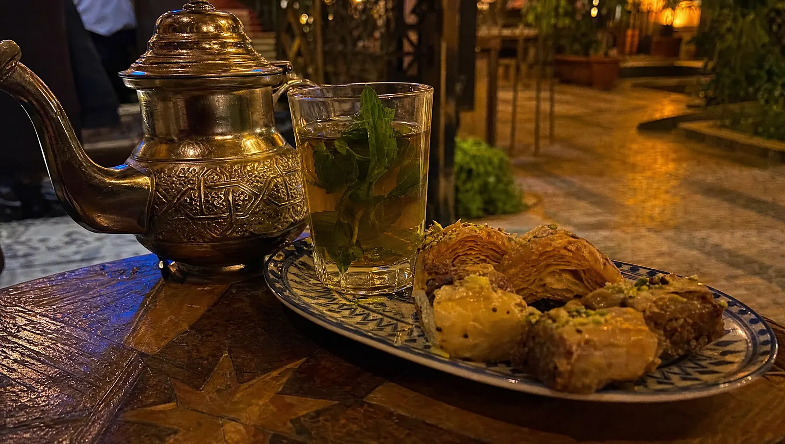 Mesa de tetería árabe con tetera, té a la menta y dulces tipo baklava