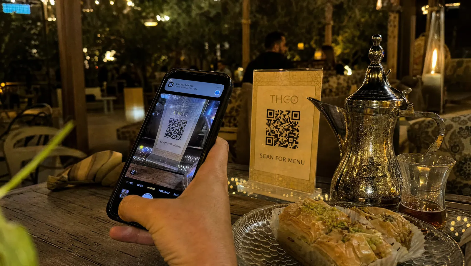 Cliente escaneando con el móvil el código QR de la carta en una mesa de tetería